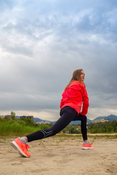 Atletik kadın sabah antrenmanından önce Forest Mountain Road 'da ısınıyor. Koşucu eğitimi, sağlıklı yaşam tarzı konsepti.. - Fotoğraf, Görsel