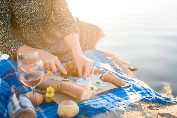 Piquenique romântico de verão para dois no mar de burega, com frutas, queijo, vinho, pão, uvas, pêssego. Luz dos primeiros raios do sol. Piquenique ao amanhecer. - Foto, Imagem
