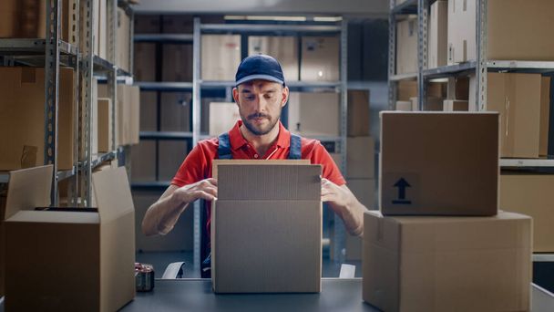 Professional Warehouse Worker Finishes Order, Sealing Cardboard Boxes Ready for Shipment. In the Background Rows of Shelves with Cardboard Boxes with Ready Orders. - Photo, Image