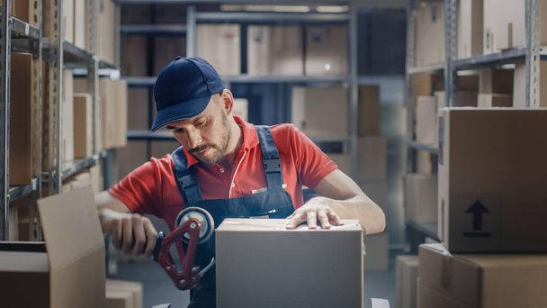 Professional Warehouse Worker Finishes Order, Sealing Cardboard Boxes Ready for Shipment. In the Background Rows of Shelves with Cardboard Boxes with Ready Orders. - Foto, afbeelding