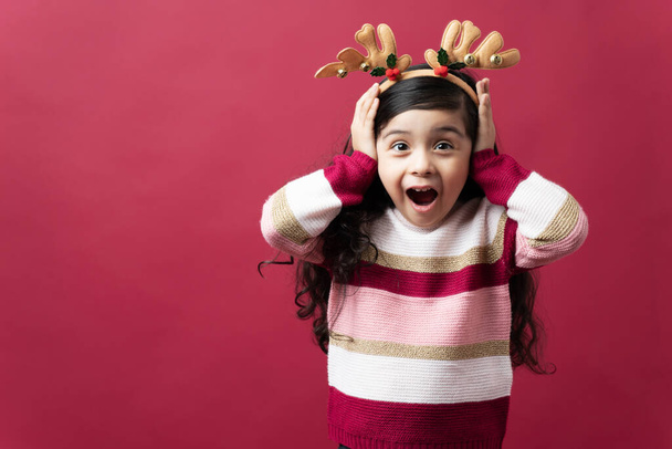 Retrato de uma menina hispânica chocado com a boca aberta animado sobre o Natal em um fundo vermelho - Foto, Imagem