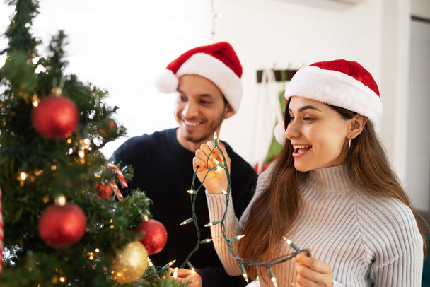 Gros plan d'un couple latin portant des décorations de Noël à la maison et s'amusant ensemble - Photo, image