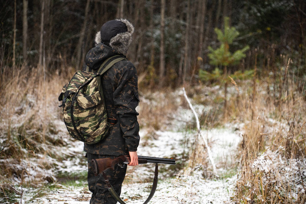 Hunter with a gun and a backpack in the winter forest - Φωτογραφία, εικόνα