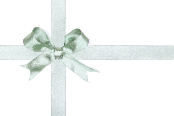 Frosty green Christmas gift bow and ribbon arranged as wrapped gift box isolated on a white background - Photo, Image