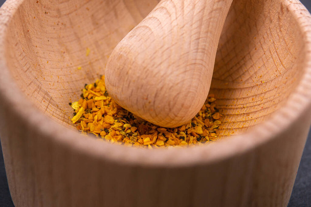 rubs spices with a mortar and pestle. Kitchen utensils and other curry spices - Foto, afbeelding