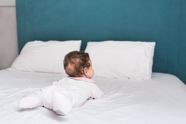 Очаровательная малышка лежит дома на кровати - Фото, изображение