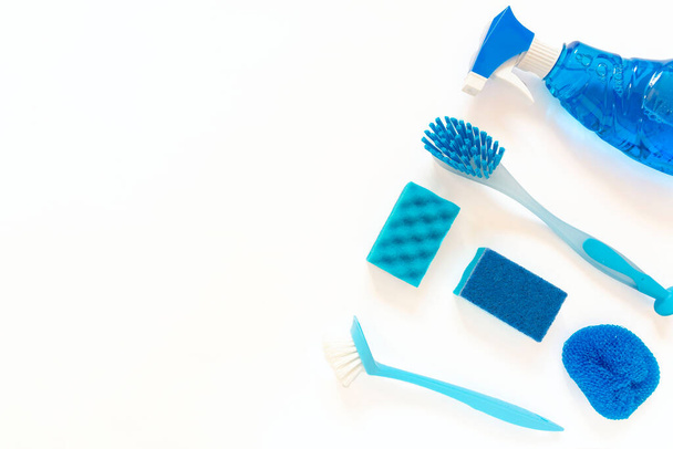 Blue cleaning kit. Bottles, spray, brushes, sponges flat lay on the white background with copy space - Φωτογραφία, εικόνα