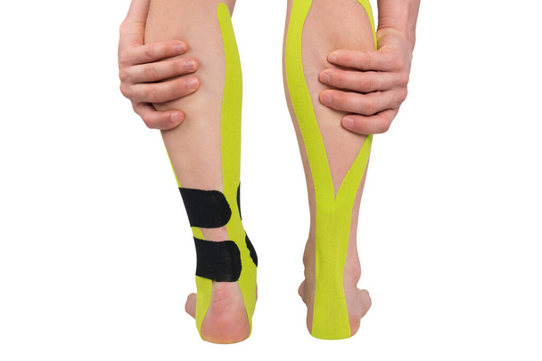 ruce držet bolavé nohy s aplikovanou lékařskou páskou pomáhá při léčbě, izolované na bílém, pohled zezadu - Fotografie, Obrázek