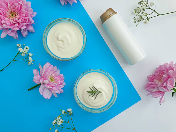 cosmetische crème, bloem op een gekleurde achtergrond - Foto, afbeelding