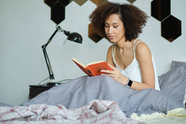 Fiatal nő kezében egy könyvet a hálószobában. - Fotó, kép