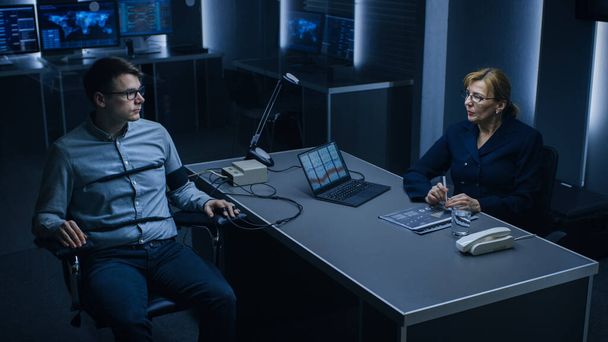 Female Special Agent Conducts Lie Detector Polygraph Test on a Young Suspect. Expert Examiner Questions Accused in Interrogation Room. Laptop Records Reactions. - 写真・画像