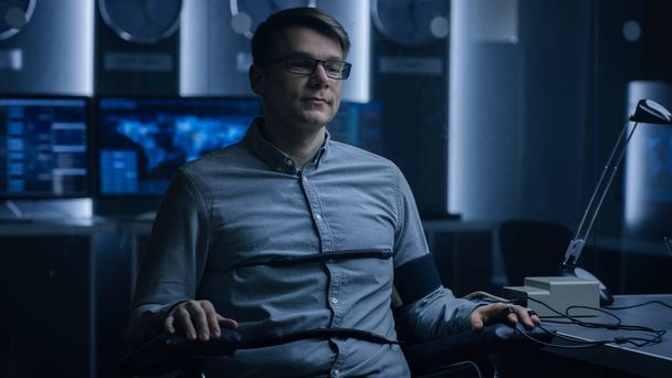 Young Handsome Suspect During Interrogation Undergoes Lie Detector Polygraph Test, Connected to the Machine He Answers Yer or No Questions Which Computer Records and Shows if Hes Lying. - Valokuva, kuva