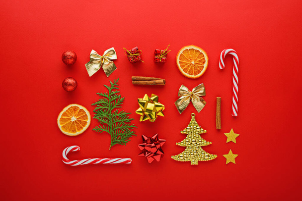 クリスマスの構図。お菓子、おもちゃ、風船、赤い背景の金のモミ、トップビュー、最小限のフラットレイアウト、新年の背景 - 写真・画像