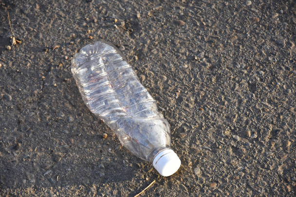 Obraz pustej plastikowej butelki, pozostawionej jako ściółka na ziemi..  - Zdjęcie, obraz