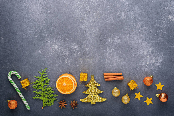 Рождественская композиция на сером фоне, конфеты, рождественские игрушки, воздушные шары, звезды, сушеный апельсин, копировальное пространство, вид сверху, меню, праздничный кухонный фон - Фото, изображение