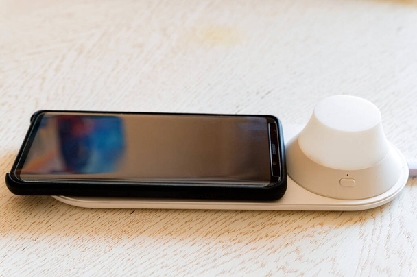 Blanco cargador de dispositivo móvil inalámbrico moderno con teléfono móvil - Foto, imagen