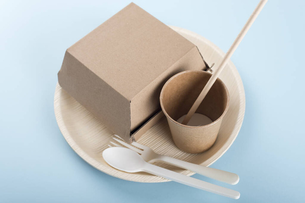 Biodegradable plate, cup, burger box and cutlery on light blue background. Recycling concept. - Photo, Image