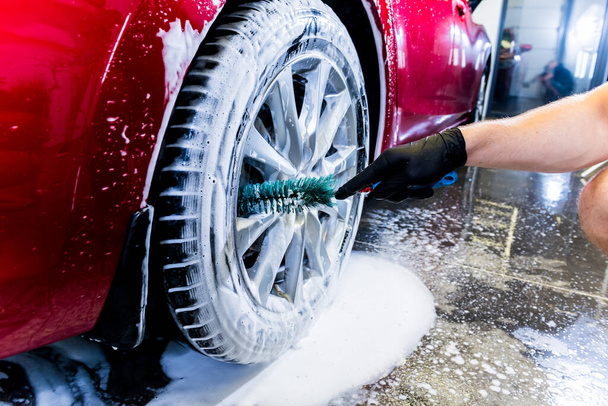 Cleaning the car wheel with a brush and water - Foto, imagen