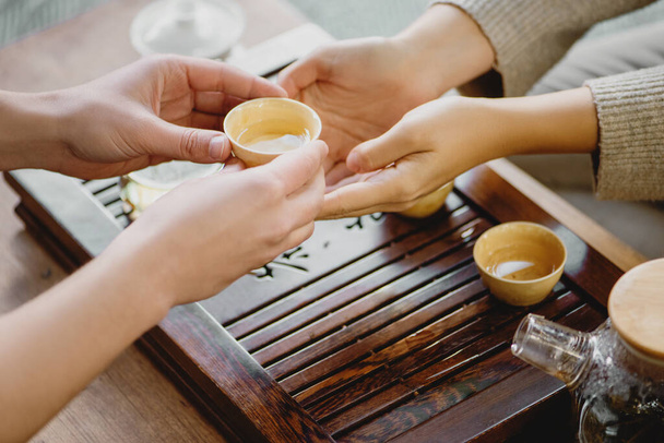 Male hands giving small porcelain cup with tea to female during a tea ceremony. - Foto, immagini