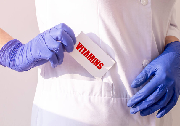 Γιατρός κρατώντας μια κάρτα με βιταμίνες κειμένου, ιατρική έννοια. - Φωτογραφία, εικόνα