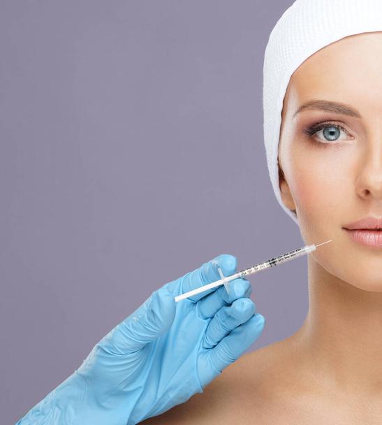 Doctor injecting in a beautiful face of a young woman. Plastic surgery, skin lifting and aesthetic medicine concept. - Foto, imagen