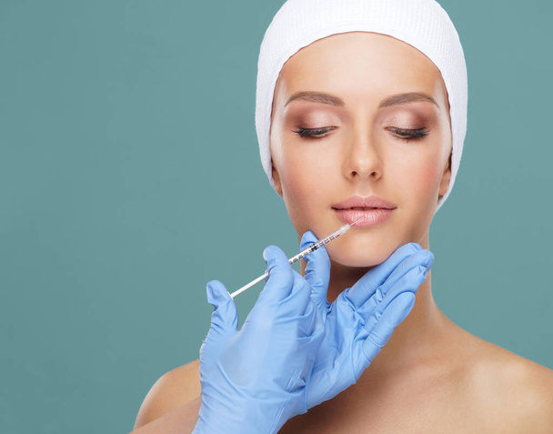 Doctor injecting in a beautiful face of a young woman. Plastic surgery, skin lifting and aesthetic medicine concept. - Photo, Image
