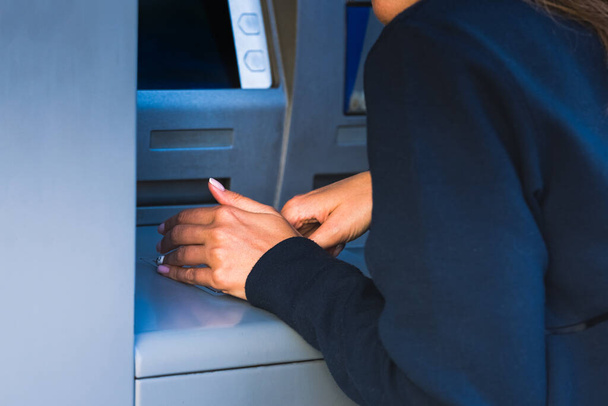 Woman cover with free hand and hide the keypad with PIN number when withdraw cash money at an ATM machine. ATM safety and security measures. Protect your PIN. High quality photo - Valokuva, kuva