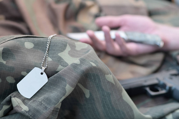 Пустой армейский жетон погибшего солдата лежит на камуфляжной одежде. Самоубийства во время военной службы в российской армии - Фото, изображение