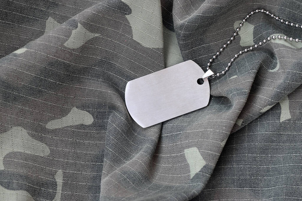 Silvery military beads with dog tag on camouflage fatigue uniform. Army token on soldiers camo jacket rear part - Photo, Image