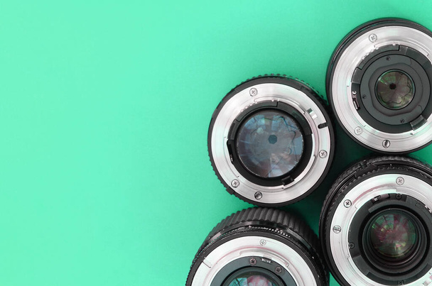 Varios lentes fotográficos se encuentran sobre un fondo turquesa brillante. Espacio para texto - Foto, imagen