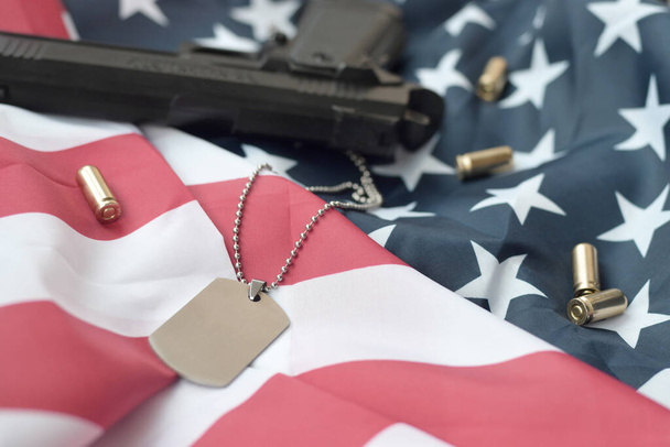 Leger Dog tag token met 9mm kogels en pistool liggen op gevouwen vlag van de Verenigde Staten. Een set van Amerikaanse militaire veteraan items of oude plicht trofee kit - Foto, afbeelding