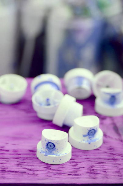 Las boquillas azules sucias del pulverizador de pintura se encuentran sobre una plancha púrpura sobre un fondo de muchas latas sucias para pintar graffiti - Foto, Imagen
