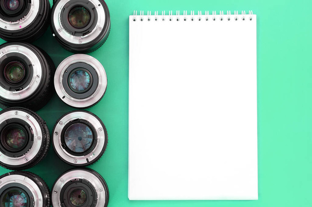 Diversi obiettivi fotografici e quaderno bianco si trovano su uno sfondo turchese brillante. Spazio per testo - Foto, immagini