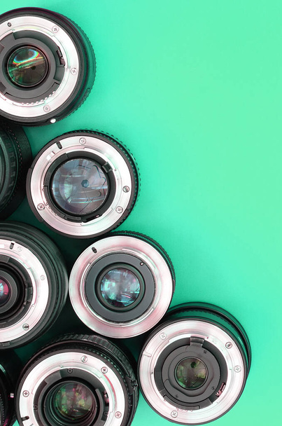 Varios lentes fotográficos se encuentran sobre un fondo turquesa brillante. Espacio para texto - Foto, imagen