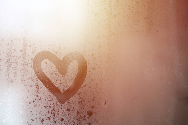 El corazón está pintado en el vidrio nebuloso en el invierno - Foto, imagen