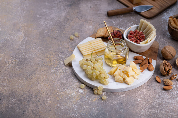 Πίνακας τυριών με απαλά τυριά, καρύδια, μέλι και σταφύλια, χώρος αντιγραφής - Φωτογραφία, εικόνα