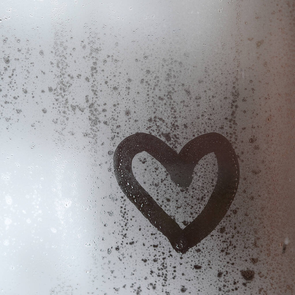El corazón está pintado en el vidrio nebuloso en el invierno - Foto, Imagen
