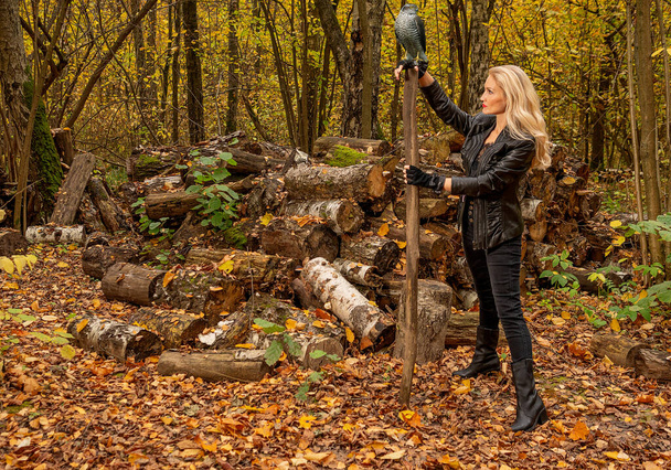 In the forest, a woman stands in a leather jacket and black jeans. Happy looking at camera concept of webinar activity - Fotografie, Obrázek