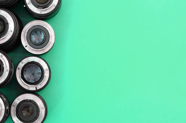 Varios lentes fotográficos se encuentran sobre un fondo turquesa brillante. Espacio para texto - Foto, Imagen