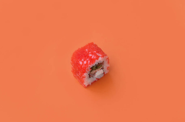 California Maki sushi roll met kaviaar en masago op oranje achtergrond close-up. Minimalisme top view flat lag met Japans eten - Foto, afbeelding