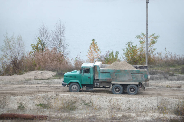Çöp kamyonu, maden ocağındaki kum ve diğer mineralleri taşıyor. Ağır sanayi ve kaynak transferi - Fotoğraf, Görsel