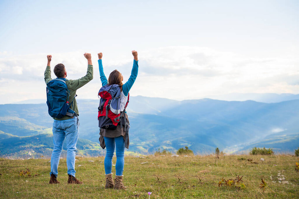 Happy travelers couple conquered top of mountain, raises hands up - Foto, immagini