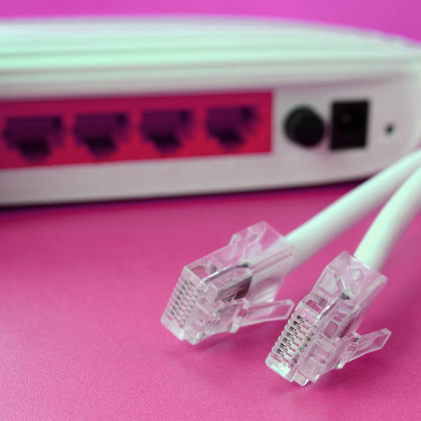 Internet router and Internet cable plugs lie on a bright pink background. Items required for Internet connection - Photo, Image