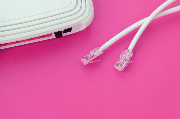 El router de Internet y los enchufes de cable de Internet se encuentran sobre un fondo rosa brillante. Elementos necesarios para la conexión a Internet - Foto, imagen