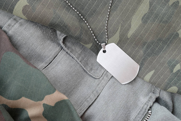 Silvery military beads with dog tag on different camouflage fatigue uniforms. Army token on soldiers camo jackets - Photo, Image
