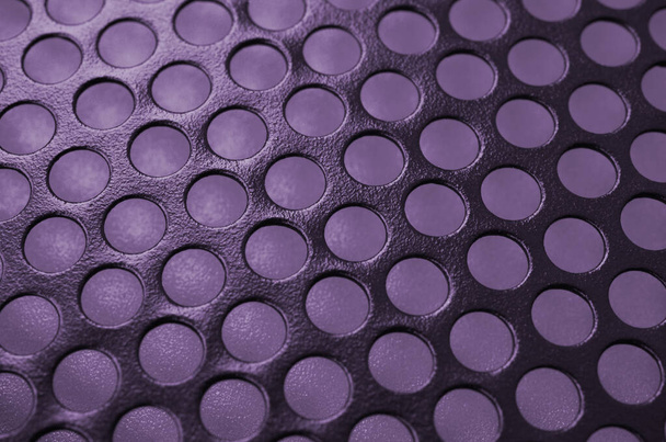 Zwart metalen computerpaneel met gaten op paarse achtergrond. Abstract close-up afbeelding - Foto, afbeelding