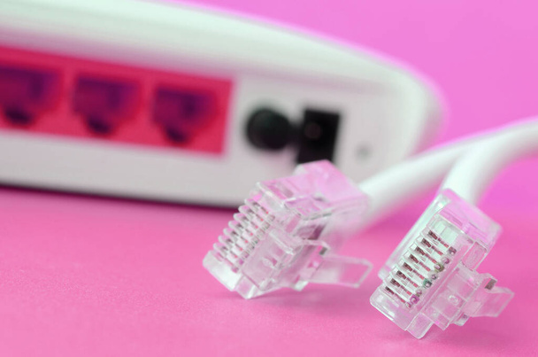 Інтернет-маршрутизатор і інтернет-кабельні плуги лежать на яскраво-рожевому фоні. Елементи, необхідні для підключення до Інтернету - Фото, зображення