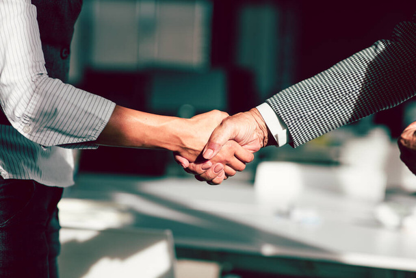 Businessman and businesswoman shaking hands above desk - Foto, afbeelding