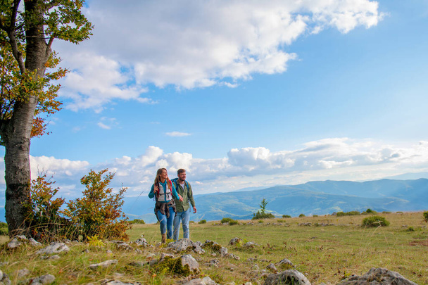 Happy couple hiking and enjoying a valley view - Фото, зображення