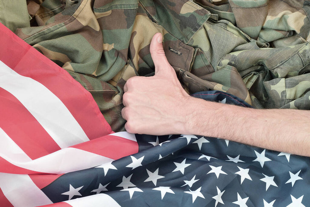 A mão mostra polegares na bandeira americana e uniforme militar. Conceito de bom serviço militar em Estados Unidos - Foto, Imagem